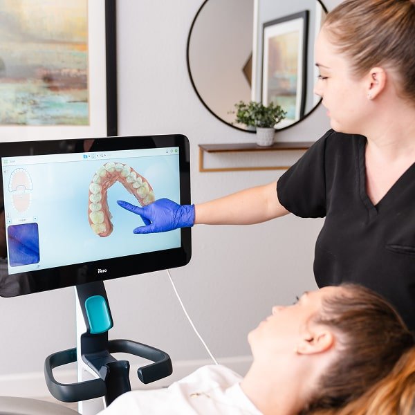 3d scan of a teeth on the screen and dental specialist with a patient near it