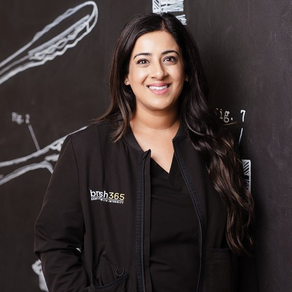 A dentist is smiling and looking at the camera