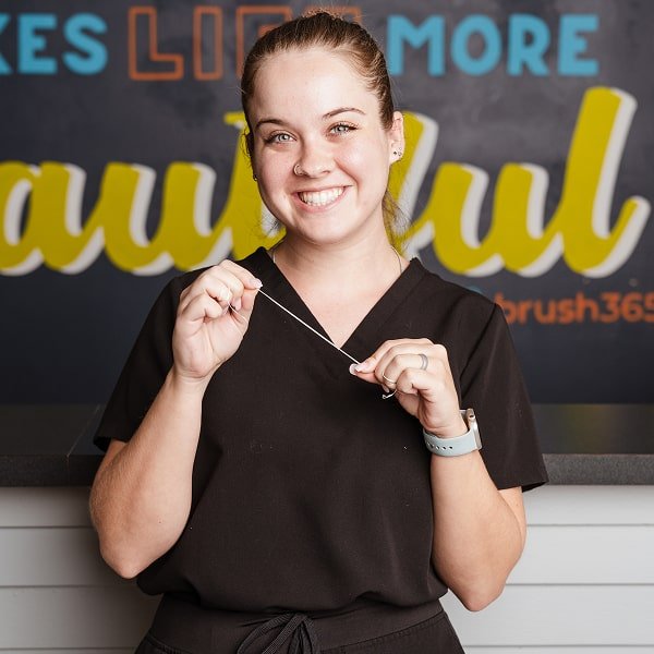 A woman is smiling with a floss in her hands
