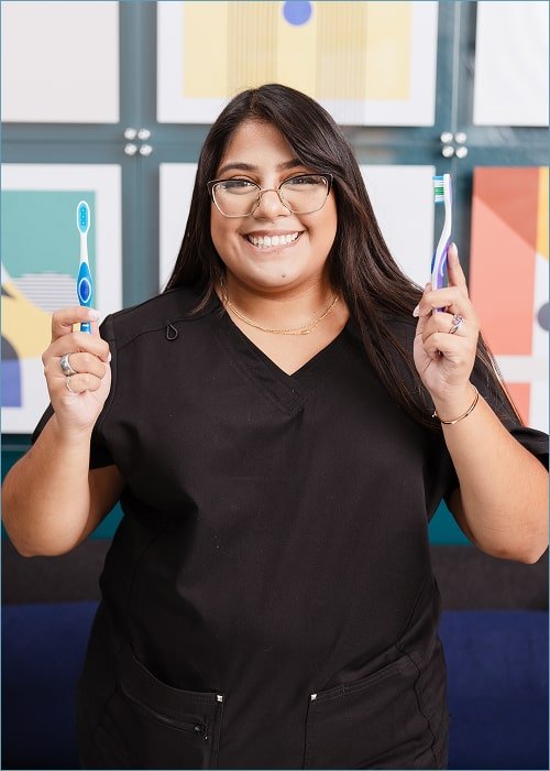 Dental expert is smiling with two toothbrushes in her hands