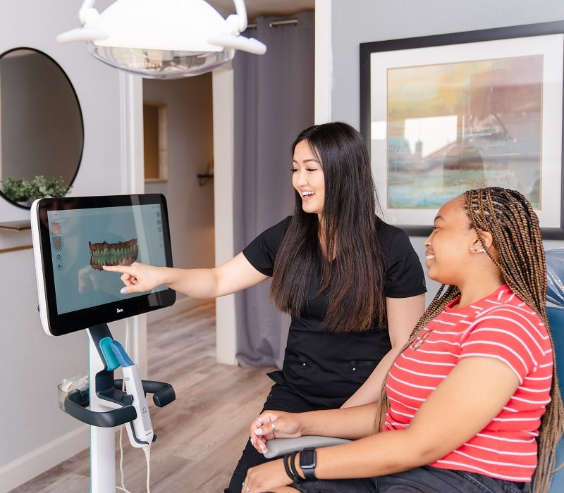 Dental professional is showcasing 3d scan of a teeth to smiling patient at brush365