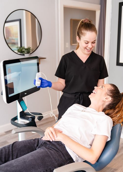 Dentist and a patient are joyfully smiling while looking at each other
