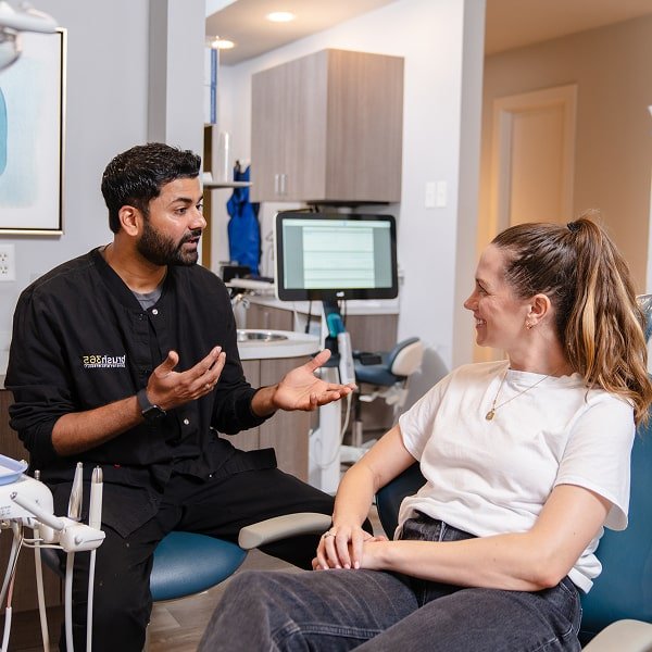Dentist answering FAQs and smiling to the patient in a dental chair