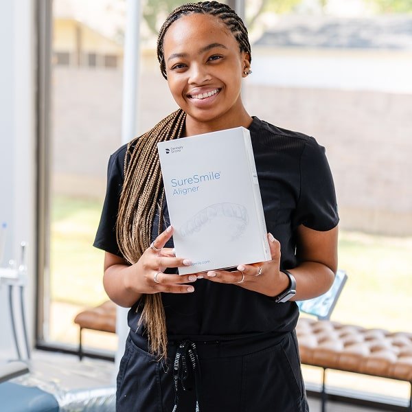 Dentist is holding SureSmile certificate and smiling