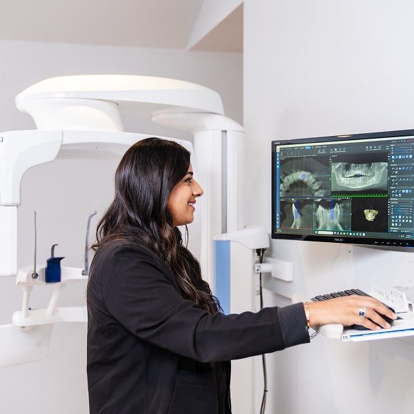A woman is joyfully smiling with two toothbrushes in her hands