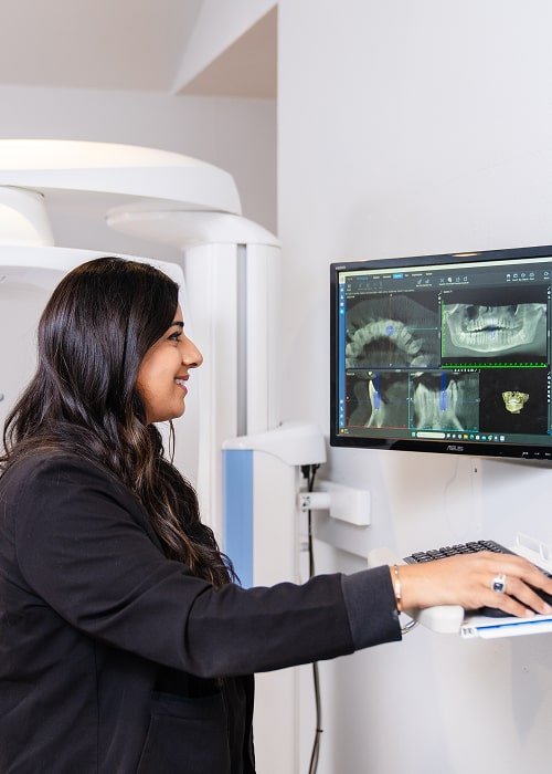 Dentist looking at 3d dental x-rays on the screen and smiling