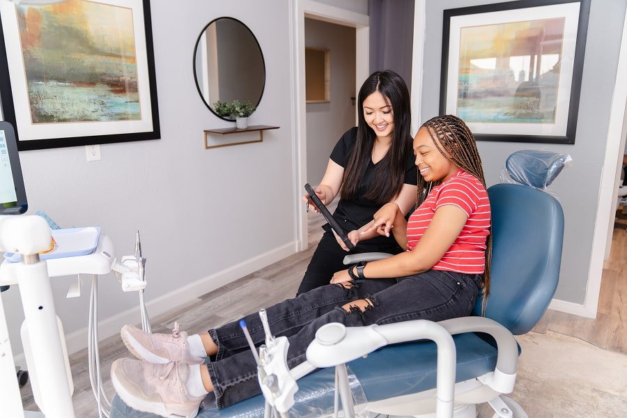 Dentist is showcasing a list of services to the dental patient in a dental chair
