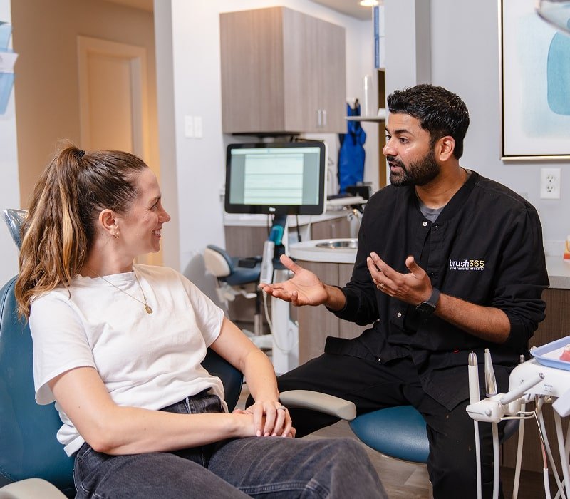 Dentist is talking to his patient and smiling