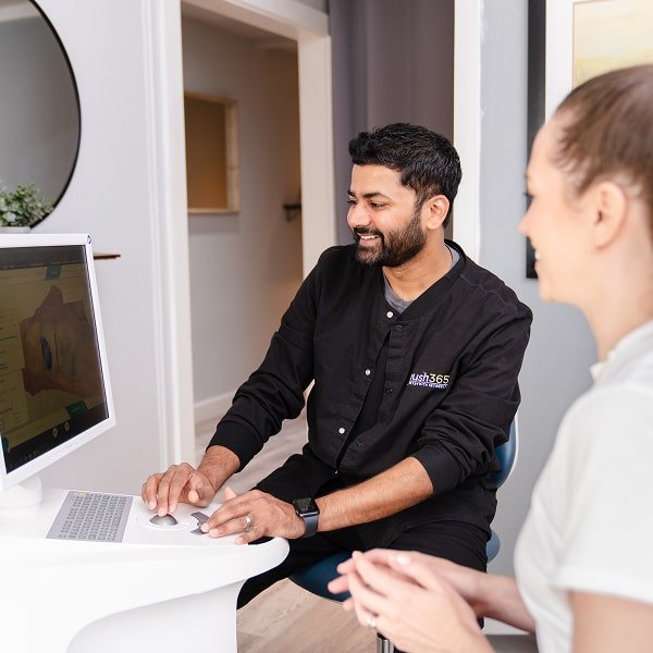 brush365 dentist is smiling while showcasing 3d dental scan to patient