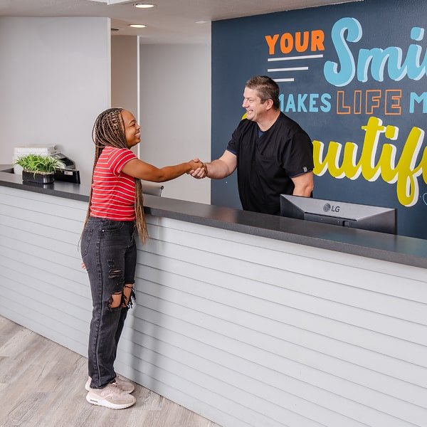 brush365 front desk is smiling and greeting smiling patient
