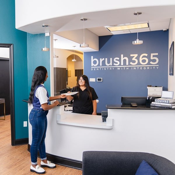 brush365 receptionist handling over financial plan to the patient and joyfully smiling