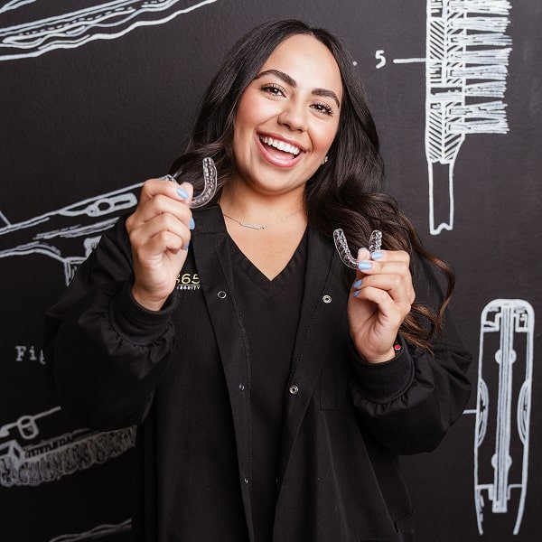 brush365 top dentist is holding SureSmile aligners and smiling