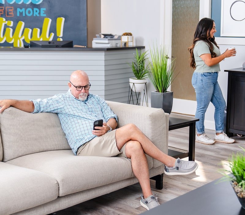 brush365 waiting room with a man sitting in a couch and reading newspaper