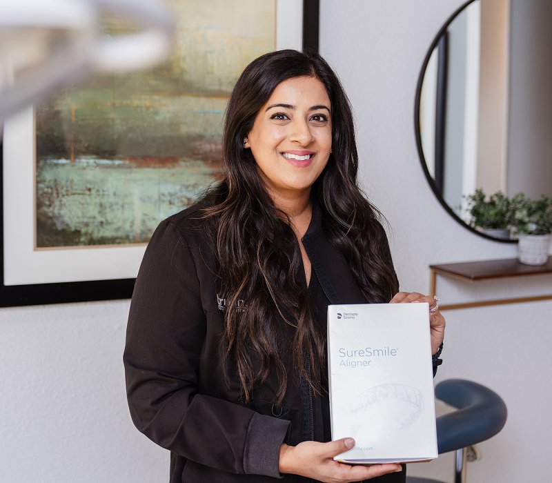 Dr. Sara Mahmood posing with a SureSmile clear aligners box