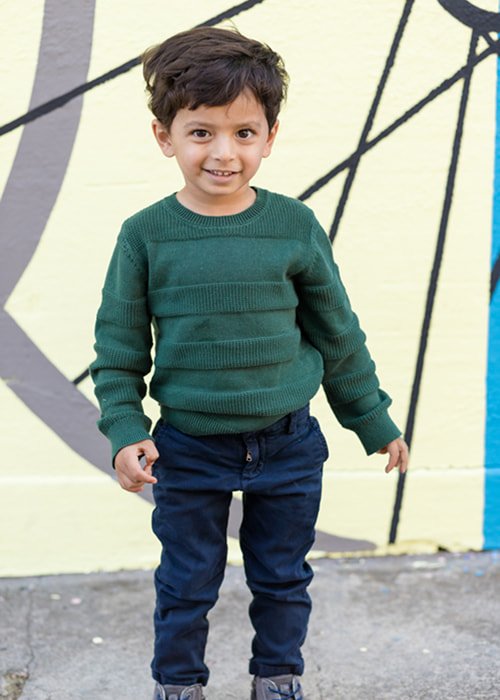 A boy in a green sweater smiling