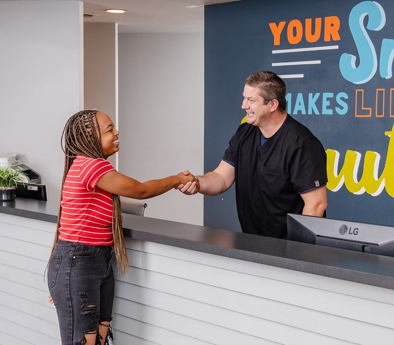 A member of brush365 reception team shaking hands with a patient