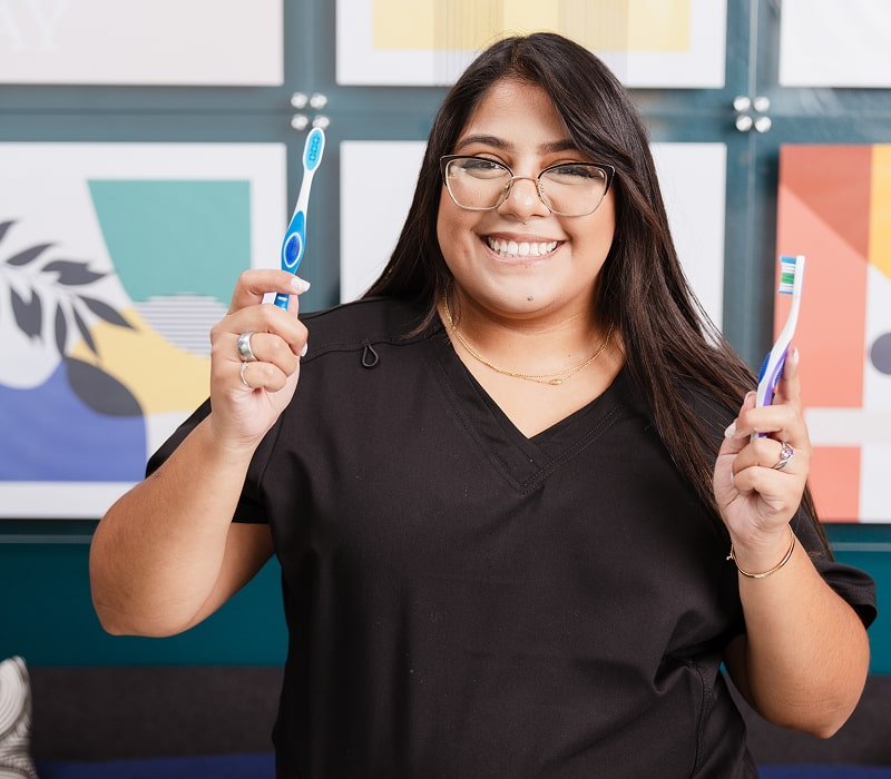 A team member holding two toothbrushes