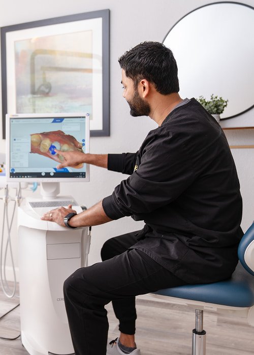 brush365 doctor pointing at a screen with a 3D model of a jaw